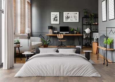 Real photo of open space apartment interior with beige sofa next to the window and desktop computer o a wooden desk Wall mural