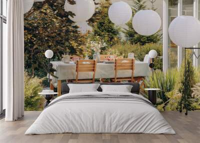 Real photo of round lamps above a table with wooden chairs in a garden Wall mural