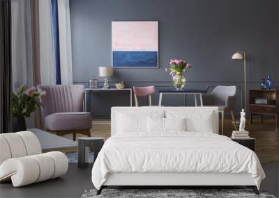 Real photo of two chairs with a table in front of a lamp and a painting, and behind an armchair and patterned rug in elegant living room interior Wall mural