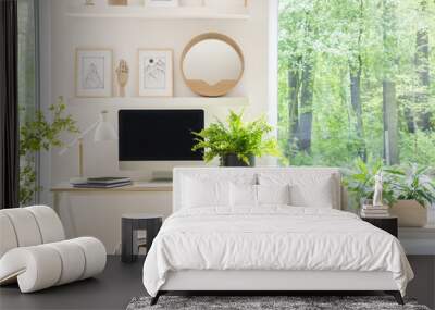 Shelves with illustrations above a wooden desk with computer by a window in a natural, white home office interior for an artist Wall mural