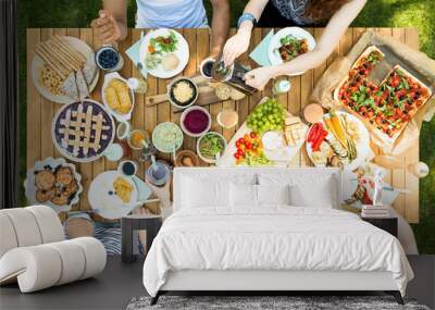 Top view of a wooden table with pizza, cherry pie, fruit, vegetables and pancakes during a vegetarian outdoor party Wall mural