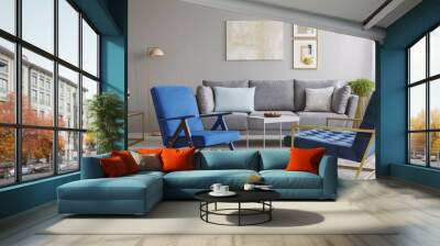 Two blue armchairs and a gray sofa standing in a living room interior with golden decorations. Real photo Wall mural