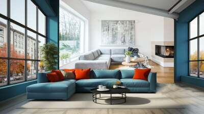 Two hairpin tables with books, tulips and coffee cup placed on white rug in bright living room interior with grey sofa, fireplace and abstract painting on the wall Wall mural