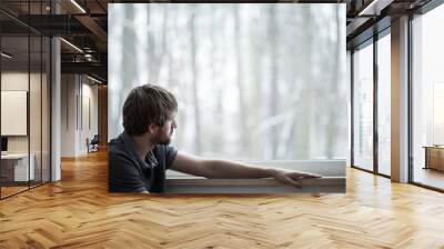 Young man sitting on the floor of living room with big window Wall mural