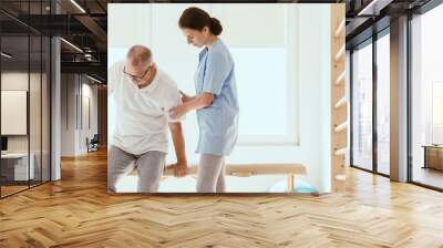 Young physiotherapist exercises in a bright medical office with Wall mural