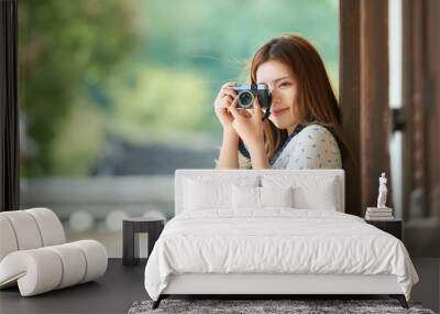 A young woman wearing a camera and taking pictures while traveling to tourist attractions with traditional Korean houses Wall mural