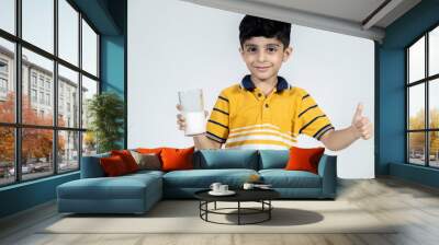 portrait of indian kid with glass of milk in hand on isolated background Wall mural