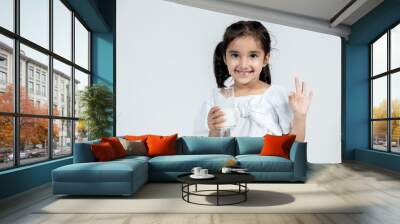 portrait of indian kid with glass of milk in hand on isolated background Wall mural