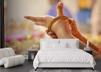 Indian woman trying bridal golden traditional wedding bangles in a shop in North India, New Delhi, India Wall mural