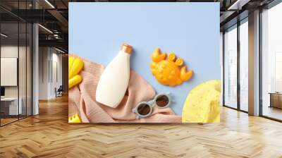 Baby sun protection cream with sand molds, sunglasses, towel on blue table. Flat lay, top view. Wall mural