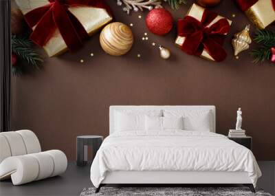 Christmas elegant holiday flat lay with gold-wrapped gifts, red ribbons, pine branches, and festive baubles on a dark brown background Wall mural