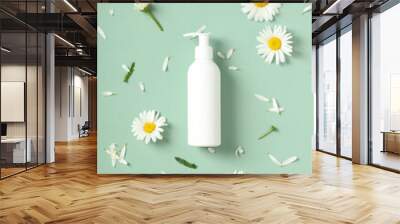 Empty white cosmetic bottle with pump and daisy flowers on green background. SPA beauty product design, branding. Wall mural