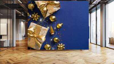 Golden Christmas decorations, gift boxes, balls, xmas trees on blue background. Flat lay, top view. Luxury Christmas postcard. Wall mural