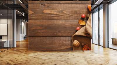 Harvest or Thanksgiving background with pumpkins, blanket, dried fall leaves, apples, red berries, walnuts on wooden table. Flat lay composition, top view, copy space Wall mural