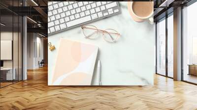 Modern office desk table top view. Flat lay keyboard, cup of coffee, paper notebook, glasses on marble background. Wall mural