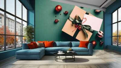 Retro style Christmas gift box with ribbon bow, candy cane, blank paper card and balls decoration on dark green background. Vintage Xmas present concept. Wall mural