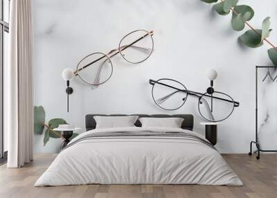 Women's glasses and eucalyptus leaves on marble table top view Wall mural