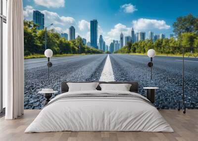 A clear view down a smooth highway leading towards a modern city skyline under bright blue skies, capturing the essence of urban progress and connectivity. Wall mural