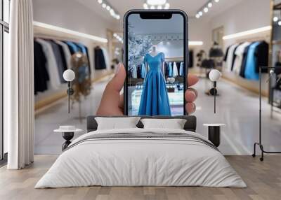 A hand holds a phone with augmented reality app in a clothing store. The screen projects an AR model of the dress. Wall mural