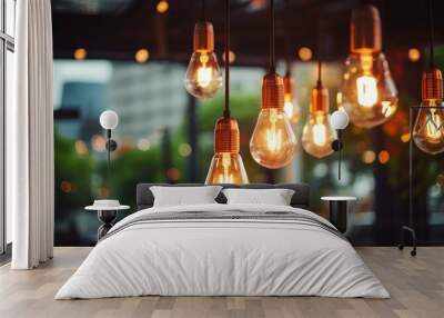 Decorative antique style light bulbs shine with orange light against a blurred evening city background. Wall mural