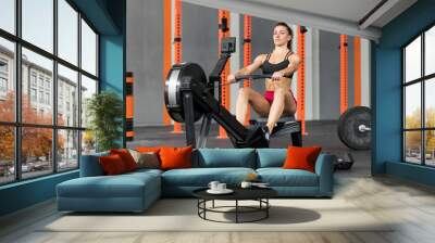 Strong sportswoman exercising on rowing machine Wall mural