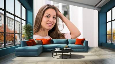 Woman looking at camera and touching hair Wall mural