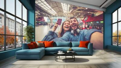 Beautiful young tourist couple in international airport, taking selfie with passport and boarding pass ready for boarding in the airplane and fly. Travel around the world concept. Wall mural