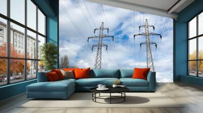 Electric pylons on sky background transporting electricity through high tension cables. Wall mural