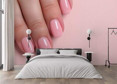 Minimalistic close-up of glossy light pink round-shaped nails on a female hand over a soft pink background, offering copy space for beauty, nail art, or pastel-themed branding visuals.

 Wall mural