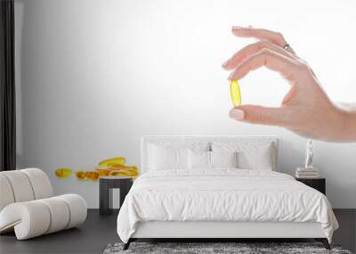 Soft gels pills with Omega-3 oil in fingers closeup on white Wall mural