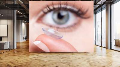 Woman eye with contact lens applying Wall mural