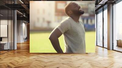 A handsome black man is feeling happy and relaxed, resting after workout in the field Wall mural