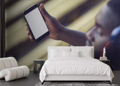 A handsome black man is holding a mock up phone screen, over shoulder view Wall mural