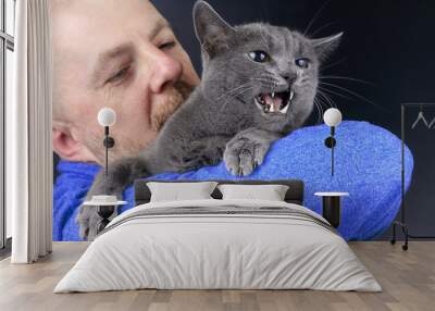 gray cat sitting on the shoulder of a man Wall mural