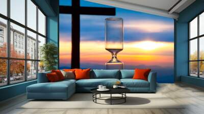 Hourglass has finished counting time on the background of the sunset and a wooden cross. End of life. The value of time in life.. Wall mural