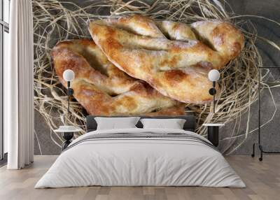 two white bread lying in straw on grey linen tablecloth Wall mural