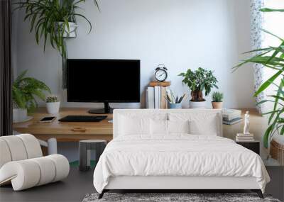 Blank screen of monitor in computer on wooden office desk in stylish business room with white wall and mock up. Light interior of office space with plants and laptop in vintage style. Banner. Wall mural