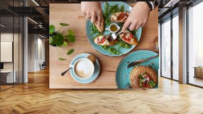 Hands of woman eat a colorful vegetarian food. Eating healthy with fresh ingredient, vegetables, breadstuff for lunch in restaurant. Close up and top view. Wall mural