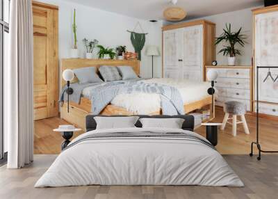 Interior in scandinavian design with wooden floor, double bed and white furniture in boho style. Grey pillows and decor in natural color. Stylish bedroom in apartment at cozy home. Hotel. Wall mural