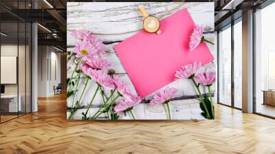 Pink paper hanging on rope with flowers on wooden white background Wall mural