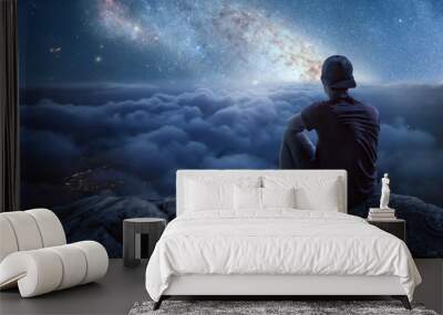 Man on a mountain looking at a beautiful starry night sky Wall mural