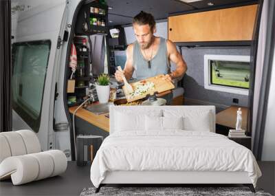 Young man cooking inside his camper van Wall mural