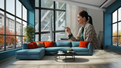 a businesswoman works at her desk, an entrepreneur is sitting and working in front of the computer to research for information on new project, female employee is in the office Wall mural