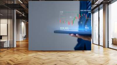 Businessman holding a device with a stock chart hologram, investing, using technology to invest in stocks. The concept of using technology in trading and analyzing stocks. Wall mural