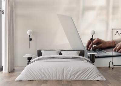 Person typing on laptop keyboard, businessman working on laptop, he is typing messages to colleagues and making financial information sheet to sum up the meeting. Wall mural