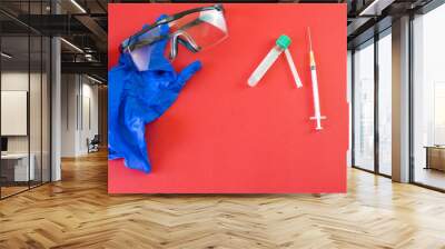 A hypodermic syringe, a plastic tube with a green cap for testing, goggles and medical protective gloves. Concept: Analysis, test, tests, viruses, vaccines, hospital protection. Wall mural