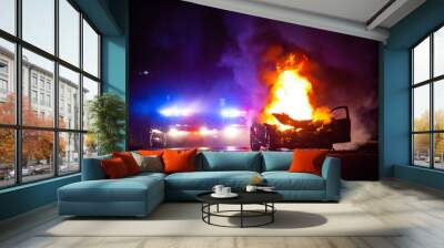 Car on fire at night with police lights in background Wall mural