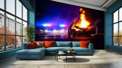 Car on fire at night with police lights in background Wall mural