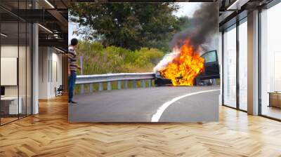 Car on fire with passengers Wall mural