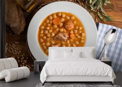 Chickpea stew dish (potage - cocido madrileño). With beef, sausage (chorizo), bacon, carrots and olive oil. Rustic appearance. Top view. Wall mural